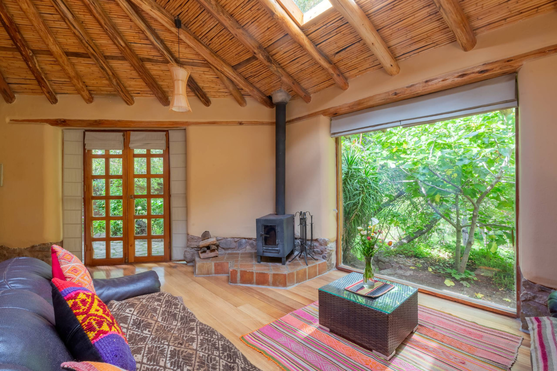 Interior acogedor de una casita con techo de madera, chimenea y ventanal al jardín