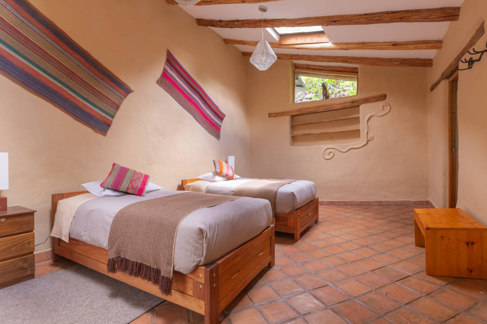 Habitación con dos camas individuales, textiles andinos y piso de terracota