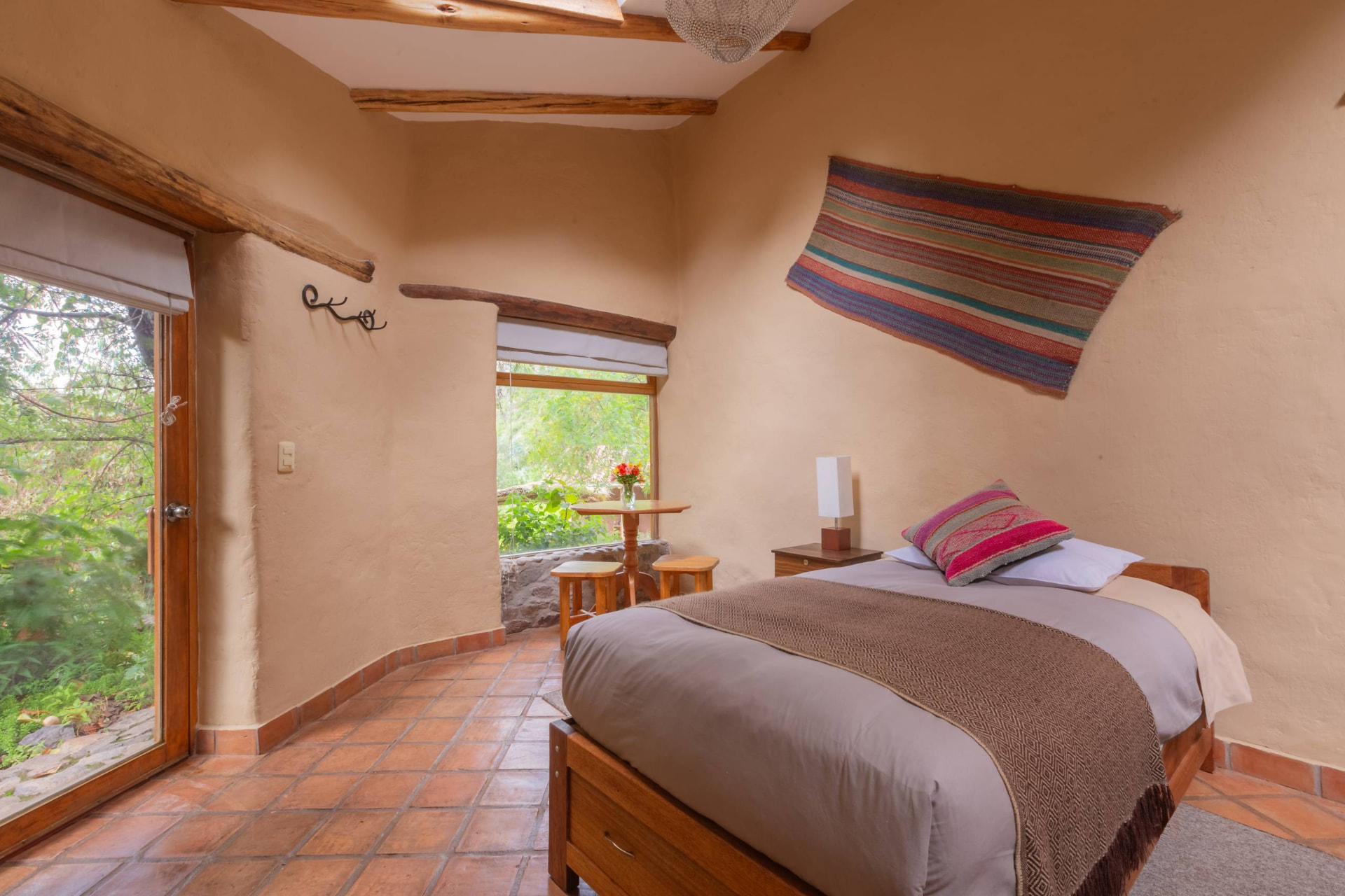 Habitación con cama matrimonial, vigas de madera y ventanal al jardín