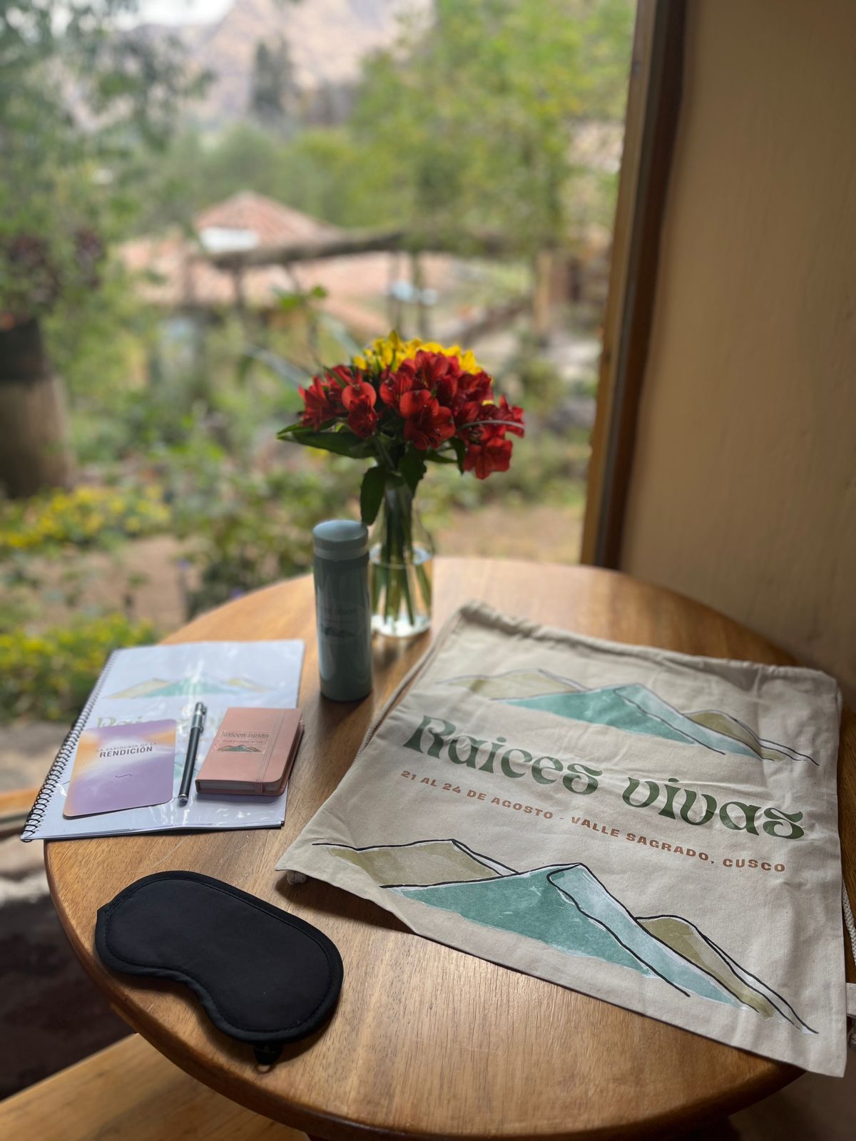 Kit del retiro: cuaderno, bolsa de tela y antifaz sobre una mesa con vista al Valle Sagrado